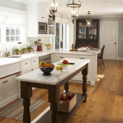 Eat-in kitchen - mid-sized traditional l-shaped medium tone wood floor eat-in kitchen idea in San Francisco with white cabinets, marble countertops, stainless steel appliances, white backsplash, ceramic backsplash, an island, a farmhouse sink and shaker cabinets
