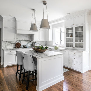 Klassische Küche in L-Form mit Landhausspüle, Glasfronten, weißen Schränken, bunter Rückwand, Rückwand aus Stein, braunem Holzboden, Kücheninsel und bunter Arbeitsplatte in Philadelphia