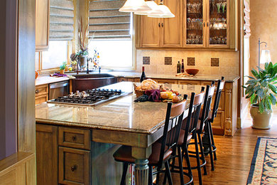 Eat-in kitchen - mid-sized traditional u-shaped medium tone wood floor eat-in kitchen idea in Portland with a farmhouse sink, shaker cabinets, light wood cabinets, granite countertops, beige backsplash, stone tile backsplash, stainless steel appliances and an island