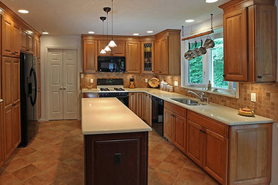 Eat-in kitchen - mid-sized traditional l-shaped ceramic tile eat-in kitchen idea in DC Metro with a double-bowl sink, raised-panel cabinets, medium tone wood cabinets, granite countertops, brown backsplash, stone tile backsplash, stainless steel appliances and an island