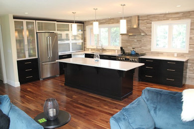 Large trendy l-shaped medium tone wood floor and brown floor open concept kitchen photo in Toronto with an undermount sink, glass-front cabinets, black cabinets, quartz countertops, gray backsplash, marble backsplash, stainless steel appliances and an island