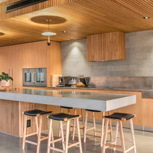 Expansive industrial l-shaped open plan kitchen in Perth with a single-bowl sink, solid surface benchtops, grey splashback, matchstick tile splashback, stainless steel appliances, ceramic floors, grey floor, grey benchtop, flat-panel cabinets, light wood cabinets, with island and wood.