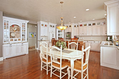 Exempel på ett stort lantligt flerfärgad flerfärgat kök, med en nedsänkt diskho, luckor med upphöjd panel, vita skåp, granitbänkskiva, vitt stänkskydd, integrerade vitvaror, mellanmörkt trägolv, en köksö, stänkskydd i tunnelbanekakel och brunt golv
