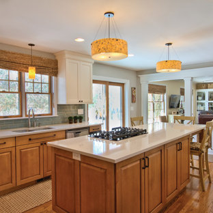 Design ideas for a mid-sized eclectic u-shaped eat-in kitchen in Detroit with an undermount sink, flat-panel cabinets, light wood cabinets, quartz benchtops, blue splashback, glass tile splashback, stainless steel appliances, medium hardwood floors and with island.