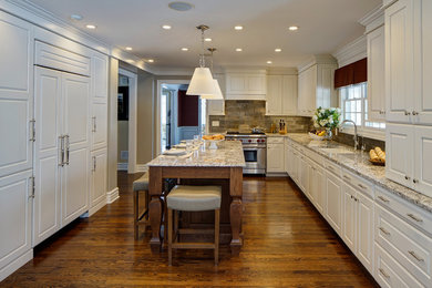 Example of a large classic u-shaped medium tone wood floor open concept kitchen design in Chicago with an undermount sink, raised-panel cabinets, white cabinets, granite countertops, metallic backsplash, stone tile backsplash, paneled appliances and an island