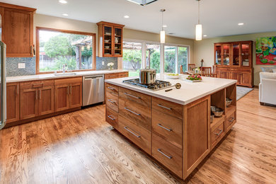Inspiration for a mid-sized craftsman l-shaped light wood floor and brown floor open concept kitchen remodel in San Francisco with an undermount sink, shaker cabinets, light wood cabinets, quartz countertops, blue backsplash, glass tile backsplash, stainless steel appliances and an island