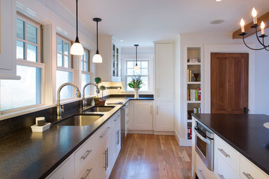 Eat-in kitchen - mid-sized transitional u-shaped medium tone wood floor eat-in kitchen idea in Burlington with an undermount sink, shaker cabinets, white cabinets, granite countertops, multicolored backsplash, subway tile backsplash, stainless steel appliances and an island