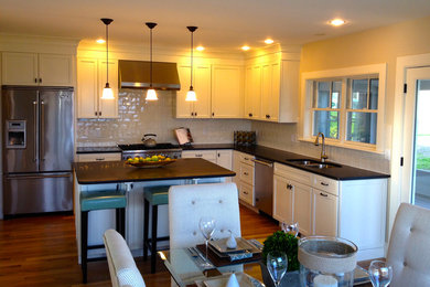 Inspiration for a mid-sized timeless l-shaped medium tone wood floor eat-in kitchen remodel in Boston with shaker cabinets, an island, white cabinets, marble countertops, white backsplash, porcelain backsplash, an undermount sink and stainless steel appliances