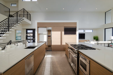 Design ideas for an expansive contemporary open plan kitchen in Other with a submerged sink, flat-panel cabinets, medium wood cabinets, engineered stone countertops, white splashback, glass sheet splashback, stainless steel appliances, concrete flooring, multiple islands, grey floors and white worktops.