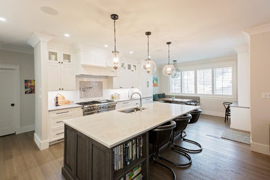 Large transitional l-shaped medium tone wood floor and brown floor eat-in kitchen photo in Other with an undermount sink, shaker cabinets, white cabinets, white backsplash, subway tile backsplash, paneled appliances, an island, gray countertops and quartz countertops
