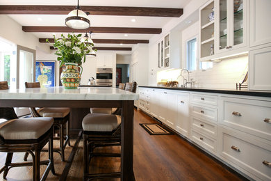 Inspiration for a large timeless single-wall medium tone wood floor open concept kitchen remodel in San Diego with an undermount sink, shaker cabinets, white cabinets, marble countertops, white backsplash, ceramic backsplash, stainless steel appliances and an island