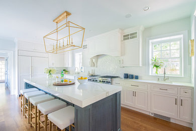 Kitchen - large transitional l-shaped medium tone wood floor and brown floor kitchen idea in Philadelphia with a farmhouse sink, white cabinets, quartzite countertops, white backsplash, marble backsplash, paneled appliances, an island, white countertops and shaker cabinets