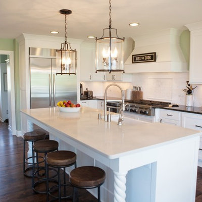 Kitchen - traditional l-shaped kitchen idea in Milwaukee with a farmhouse sink, shaker cabinets, white cabinets, white backsplash and stainless steel appliances