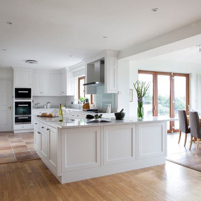 Eat-in kitchen - transitional u-shaped eat-in kitchen idea in Dublin with an undermount sink, beaded inset cabinets, white cabinets, gray backsplash, stone slab backsplash and stainless steel appliances