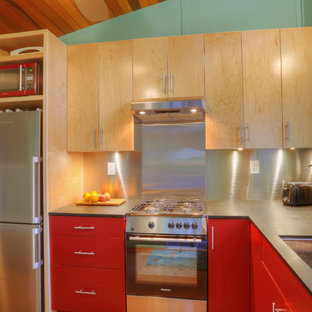 Imagen de cocina en L, moderna, pequeña, abierta, sin isla, con fregadero bajoencimera, armarios con paneles lisos, puertas de armario rojas, encimera de acrílico, salpicadero metalizado, electrodomésticos de acero inoxidable y suelo de corcho