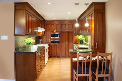 Eat-in kitchen - small tropical u-shaped bamboo floor and brown floor eat-in kitchen idea in Dallas with an undermount sink, raised-panel cabinets, medium tone wood cabinets, granite countertops, multicolored backsplash, paneled appliances, a peninsula, slate backsplash and green countertops