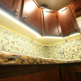 Mid-sized contemporary l-shaped eat-in kitchen in Jacksonville with a farmhouse sink, shaker cabinets, brown cabinets, granite benchtops, beige splashback, glass tile splashback, stainless steel appliances, porcelain floors and no island.