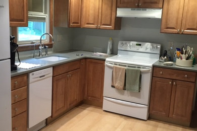 Eat-in kitchen - mid-sized transitional l-shaped light wood floor eat-in kitchen idea in Providence with an integrated sink, raised-panel cabinets, medium tone wood cabinets, quartz countertops, gray backsplash, white appliances and no island