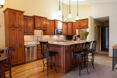 Example of a mid-sized classic l-shaped light wood floor open concept kitchen design in Minneapolis with an undermount sink, raised-panel cabinets, medium tone wood cabinets, granite countertops, beige backsplash, cement tile backsplash, stainless steel appliances and an island