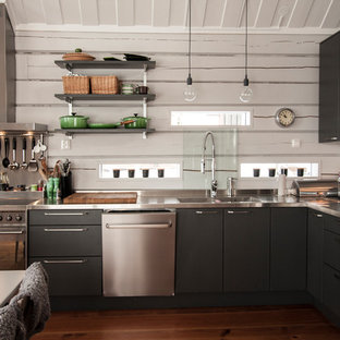 Inspiration for a medium sized urban l-shaped kitchen/diner in Gothenburg with a double-bowl sink, flat-panel cabinets, black cabinets, stainless steel worktops, stainless steel appliances and medium hardwood flooring.