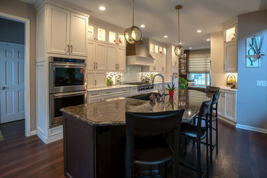 Example of a transitional medium tone wood floor kitchen design in Other with an undermount sink, recessed-panel cabinets, white cabinets, quartz countertops, beige backsplash, glass tile backsplash and stainless steel appliances