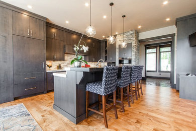 Inspiration for a large modern l-shaped brown floor and light wood floor eat-in kitchen remodel in Salt Lake City with a farmhouse sink, flat-panel cabinets, dark wood cabinets, quartzite countertops, gray backsplash, stone slab backsplash, stainless steel appliances, an island and gray countertops