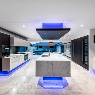 Design ideas for an expansive contemporary galley open plan kitchen in Brisbane with an undermount sink, glass-front cabinets, beige cabinets, marble benchtops, black splashback, mirror splashback, black appliances, travertine floors, with island and beige floor.