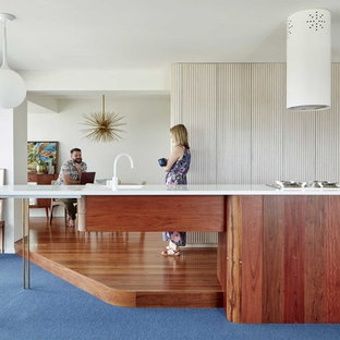 This is an example of a small midcentury galley open plan kitchen in Brisbane with a single-bowl sink, medium wood cabinets, marble benchtops, stainless steel appliances, dark hardwood floors, with island, brown floor and white benchtop.