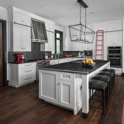 Inspiration for a coastal l-shaped dark wood floor and brown floor kitchen remodel in Detroit with an undermount sink, shaker cabinets, white cabinets, gray backsplash, stone slab backsplash, stainless steel appliances, an island and gray countertops
