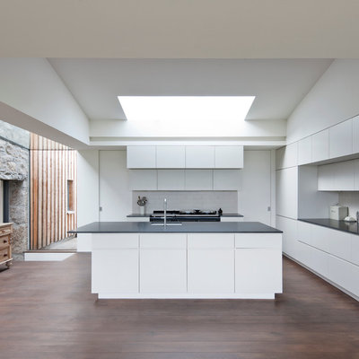 Trendy medium tone wood floor kitchen photo in Other with an undermount sink, flat-panel cabinets, white cabinets, white backsplash, subway tile backsplash and an island