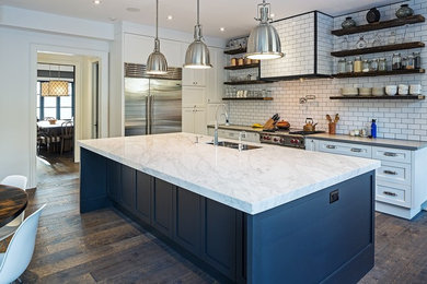 Inspiration for a large transitional dark wood floor kitchen remodel in Toronto with a double-bowl sink, recessed-panel cabinets, white cabinets, granite countertops, white backsplash, ceramic backsplash, stainless steel appliances and an island
