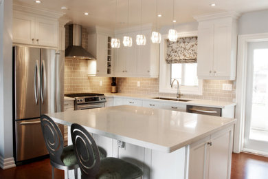 Inspiration for a mid-sized contemporary u-shaped vinyl floor eat-in kitchen remodel in Toronto with a double-bowl sink, recessed-panel cabinets, white cabinets, quartz countertops, beige backsplash, subway tile backsplash, stainless steel appliances and an island