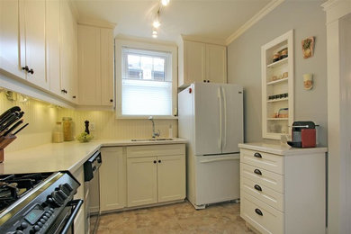 Enclosed kitchen - mid-sized traditional u-shaped ceramic tile and brown floor enclosed kitchen idea in Toronto with an undermount sink, shaker cabinets, white cabinets, laminate countertops, white backsplash, wood backsplash, white appliances and no island