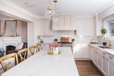Inspiration for a large timeless l-shaped medium tone wood floor and brown floor eat-in kitchen remodel in Toronto with an undermount sink, recessed-panel cabinets, white cabinets, marble countertops, white backsplash, porcelain backsplash, stainless steel appliances and an island