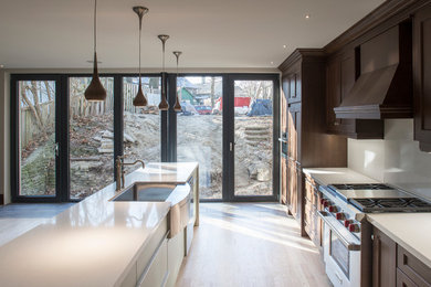 Example of a mid-sized transitional galley light wood floor open concept kitchen design in Toronto with a farmhouse sink, shaker cabinets, dark wood cabinets, quartzite countertops, white backsplash, ceramic backsplash, stainless steel appliances and an island