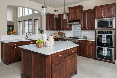 Inspiration for a mid-sized southwestern l-shaped kitchen remodel in Dallas with an undermount sink, shaker cabinets, dark wood cabinets, white backsplash, ceramic backsplash, stainless steel appliances, an island and white countertops