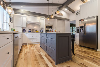 Exempel på ett avskilt, stort klassiskt u-kök, med en undermonterad diskho, skåp i shakerstil, vita skåp, bänkskiva i kvartsit, vitt stänkskydd, stänkskydd i tunnelbanekakel, rostfria vitvaror, mellanmörkt trägolv, en köksö och brunt golv