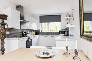 This is an example of a contemporary kitchen/diner in Other with white cabinets, grey splashback and integrated appliances.