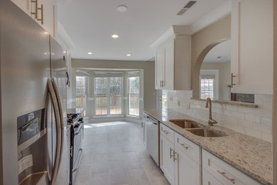 Mid-sized minimalist galley medium tone wood floor and brown floor enclosed kitchen photo in Charlotte with shaker cabinets, white cabinets, ceramic backsplash, no island, white backsplash and stainless steel appliances