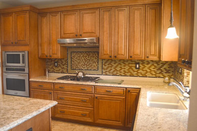 Example of a mid-sized trendy l-shaped porcelain tile eat-in kitchen design in San Diego with a double-bowl sink, medium tone wood cabinets, granite countertops, multicolored backsplash, glass tile backsplash, stainless steel appliances, an island and raised-panel cabinets