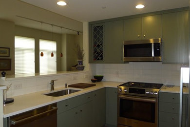 Example of a small transitional u-shaped medium tone wood floor kitchen design in Philadelphia with an undermount sink, flat-panel cabinets, green cabinets, quartzite countertops, white backsplash, porcelain backsplash and stainless steel appliances