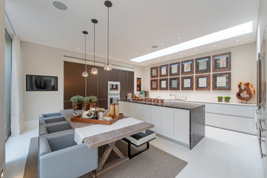 Photo of a contemporary kitchen/diner in London with a submerged sink, flat-panel cabinets, white cabinets, white appliances, an island and white floors.