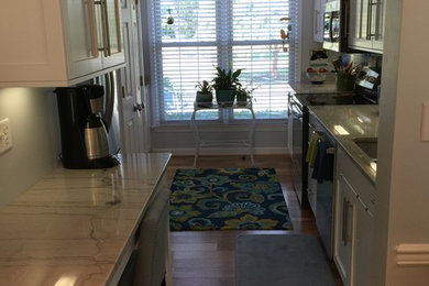 Example of a beach style medium tone wood floor kitchen design in Other with an undermount sink, flat-panel cabinets, white cabinets, quartzite countertops, blue backsplash, glass tile backsplash and stainless steel appliances