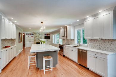 Inredning av ett modernt mellanstort vit vitt kök, med en undermonterad diskho, skåp i shakerstil, vita skåp, bänkskiva i kvarts, grått stänkskydd, stänkskydd i mosaik, rostfria vitvaror, ljust trägolv, en köksö och brunt golv