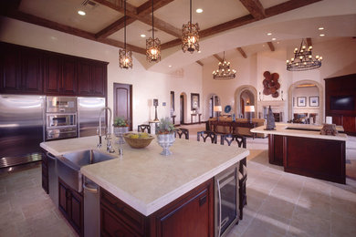 Exempel på ett stort 50 tals kök, med en rustik diskho, luckor med upphöjd panel, skåp i mörkt trä, granitbänkskiva, rostfria vitvaror, kalkstensgolv och flera köksöar
