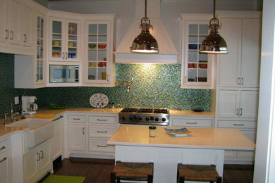 Eat-in kitchen - mid-sized coastal l-shaped dark wood floor and brown floor eat-in kitchen idea in Miami with a farmhouse sink, shaker cabinets, white cabinets, solid surface countertops, multicolored backsplash, mosaic tile backsplash, stainless steel appliances and an island