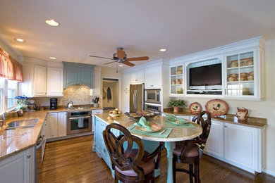 Photo of a large classic u-shaped kitchen in Cincinnati with a submerged sink, white cabinets, beige splashback, mosaic tiled splashback, stainless steel appliances, medium hardwood flooring, an island, granite worktops, brown floors, beige worktops and raised-panel cabinets.