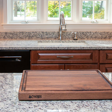 Traditional Cognac/Antique Black Cherry stain finishes with Crema Pearl Granite