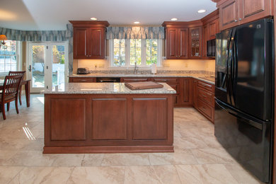 Example of a large classic galley porcelain tile and beige floor eat-in kitchen design in Manchester with subway tile backsplash, black appliances, raised-panel cabinets, dark wood cabinets, granite countertops, white backsplash, an island, yellow countertops and a single-bowl sink