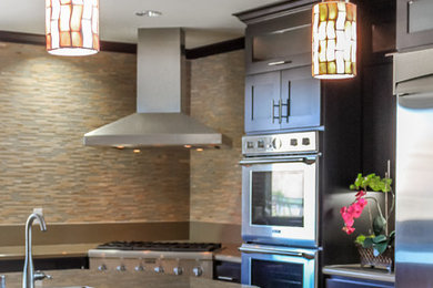 Medium sized classic l-shaped kitchen pantry in San Francisco with a submerged sink, recessed-panel cabinets, dark wood cabinets, granite worktops, beige splashback, matchstick tiled splashback, stainless steel appliances, medium hardwood flooring and a breakfast bar.